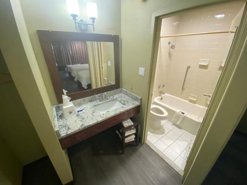 Americas Best Value Inn - Wilson في ويلسون: حمام مع حوض وحوض استحمام ومرحاض