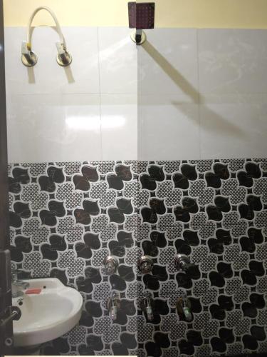 a bathroom with a black and white tile floor and a sink at HOTEL AWADH KAILASH in Bahraich