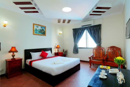 a bedroom with a bed and a chair and a table at Angkor Mithona Guesthouse in Phnom Penh
