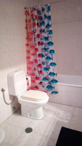a bathroom with a toilet and a shower curtain with fishes at Rua 5 House in Gafanha da Vagueira