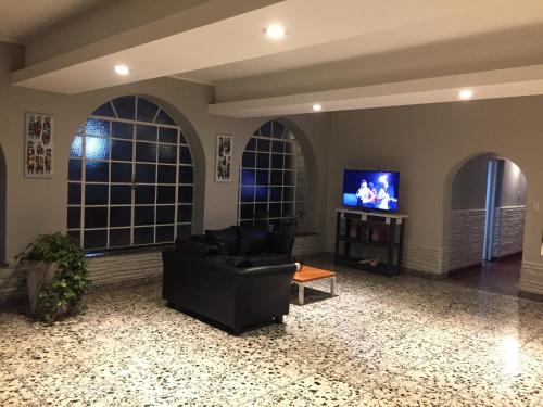 Una sala de estar con un sofá negro y un televisor. en Continental Hotel, en Curuzú Cuatiá
