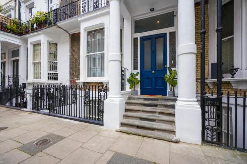 uma casa branca com uma porta azul e escadas em CG Kensington em Londres