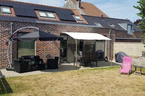 a patio with a table and an umbrella and chairs at La renaissance in Villers-lʼÉvêque
