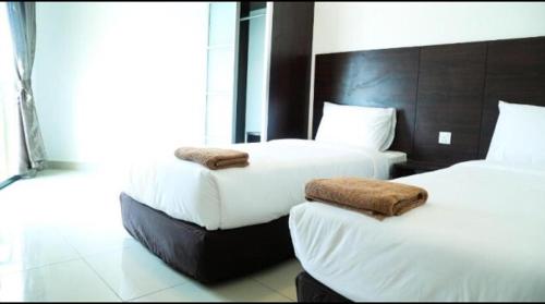 una camera d'albergo con due letti con asciugamani sopra di Marina Height Seaview Resort Apartment a Lumut