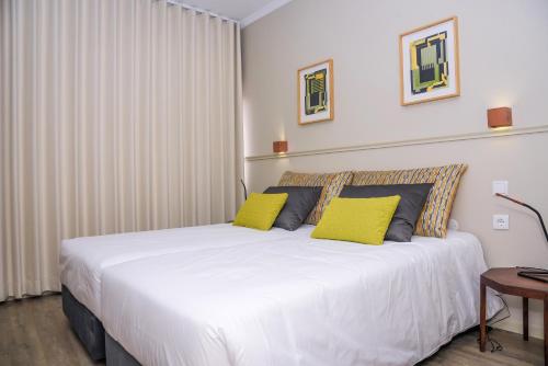 a bedroom with a large bed and a large window at Hotel Singular Porto Aeroporto in Maia