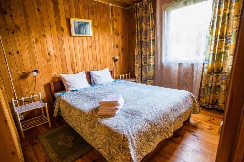 a bedroom with a bed with wooden walls and a window at Guest House Baltās Dūjas in Saulkrasti
