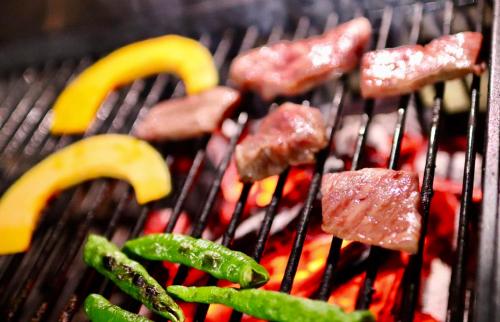 a bunch of meat and vegetables on a grill at Guesthouse All you need - All rooms have an ocean view! in Shimoda