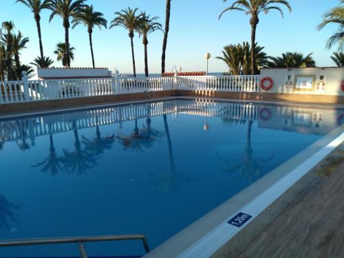 een zwembad met palmbomen en een wit hek bij Estrella de Mar in Los Urrutias
