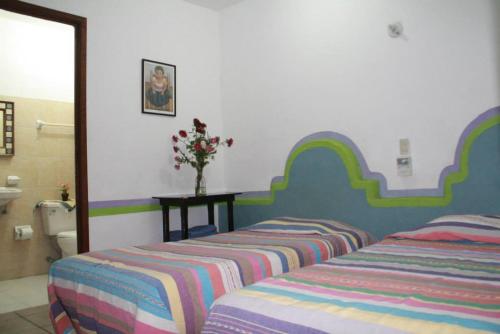 two beds sitting in a room with a bathroom at Pargos Hotel & Cowork in Puerto Escondido