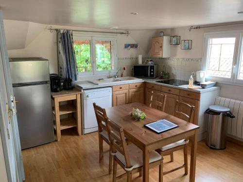 eine Küche mit einem Tisch, einem Kühlschrank und einer Spüle in der Unterkunft Manoir de la Vente de Rouville in Mesnil-Raoul