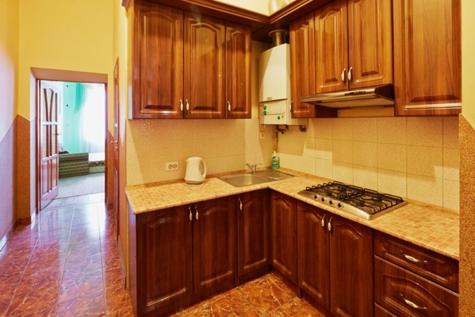 uma cozinha com armários de madeira, um lavatório e um fogão em Кулиша 25-Трёхкомнатная возле Оперы em Lviv