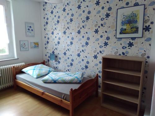 1 dormitorio con 1 cama con flores azules en la pared en Ferienwohnung Colin im schönen Weserbergland Nähe Freizeitpark, en Salzhemmendorf