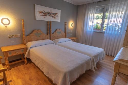 1 dormitorio con 2 camas con sábanas blancas y ventana en Hotel Río Cea, en Puente-Almuhey