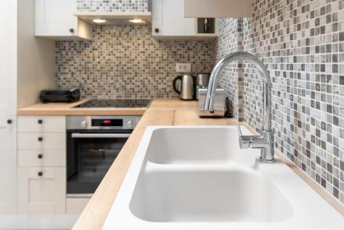 uma cozinha branca com um lavatório e um fogão em Lindos orchid villa em Lindos