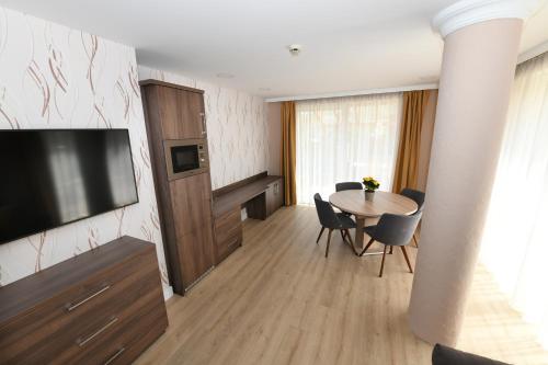 sala de estar con mesa y TV de pantalla plana en Jade Hotel-Ezüsthíd Hotel, en Veszprém