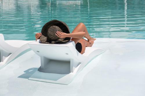 a woman sitting on top of a white surfboard in the water at Imperial Med Resort & Spa in Kamari