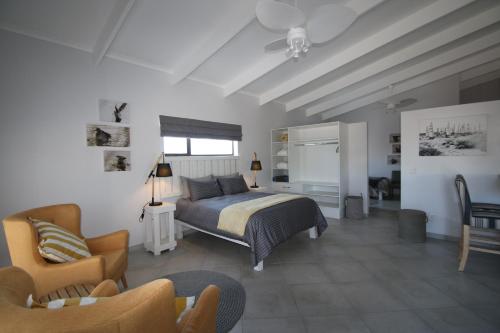 um quarto com uma cama, um sofá e uma cadeira em Albatross Guesthouse em Langebaan