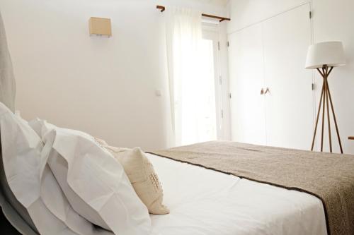 a white bedroom with a bed with white pillows at Casas da Chaminé Eco Country Lodge in Nordeste
