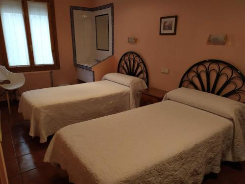 a hotel room with two beds and a mirror at PENSIÓN PEÑA in Burgos