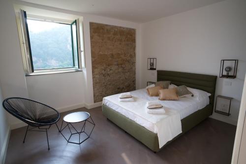 a bedroom with a bed and a chair and a window at Calamarina B&B in Vietri sul Mare