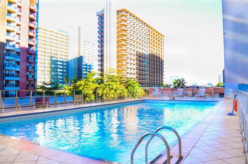 a large swimming pool in a city with tall buildings at Garvey Apart Hotel in Brasilia