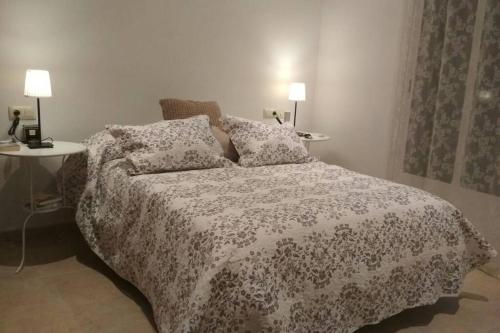 a bedroom with a bed with a flowered blanket and two lamps at Beautiful House Sierrecilla in Humilladero