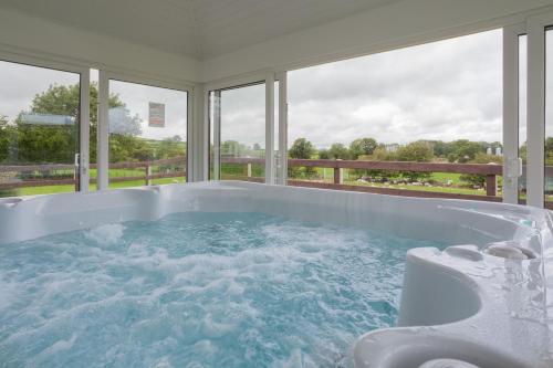 Beautiful mountain views & private hot tub في Kilcoo: حوض استحمام كبير في غرفة مع نوافذ