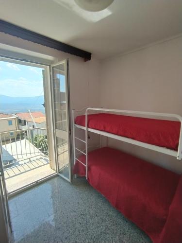 Zimmer mit einem roten Etagenbett und einem Balkon in der Unterkunft Appartamento La terrazza in Baunei
