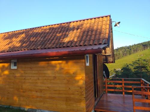 a wooden cabin with a deck with a hill in the background at Andrića Sokak 2 in Divčibare
