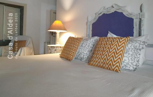 a bedroom with a white bed with pillows and a lamp at Casa d'Aldeia de Souto de Lafões OLIVEIRA DE FRADES in Oliveira de Frades