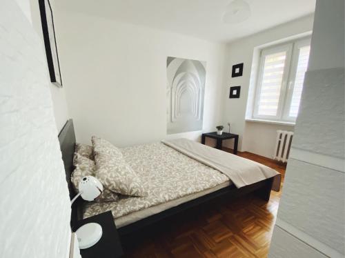Habitación blanca con cama y ventana en Apartament 23, en Tarnów