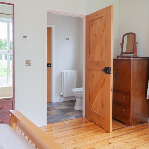 a bathroom with a toilet and a wooden door at Beautiful mountain views & private hot tub in Kilcoo