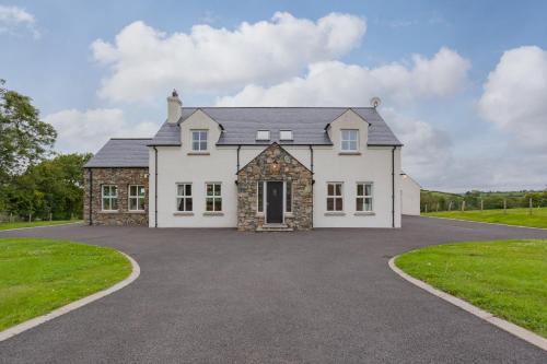a large white house with a driveway at Beautiful mountain views & private hot tub in Kilcoo