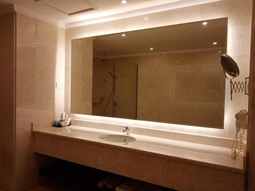 uma casa de banho com um lavatório e um espelho grande em Khabti Grand Hotel em Qal'at Bishah
