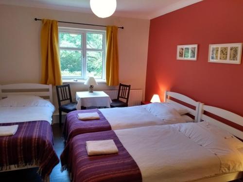 a bedroom with two beds and a table and a window at Kilcommon Lodge Holiday Hostel in Belmullet