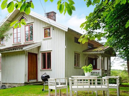 una casa con dos bancos blancos delante de ella en 7 person holiday home in UDDEVALLA en Uddevalla