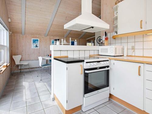 een keuken met witte kasten en een fornuis met oven bij 8 person holiday home in Henne in Henne Strand