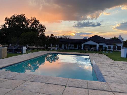 una piscina frente a una casa con puesta de sol en Steenkoppies estate semi self catering unit 1 en Magaliesburg