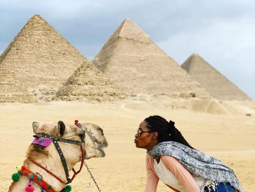a woman with a camel in front of the pyramids at Draz pyramids view Bed & breakfast in Cairo