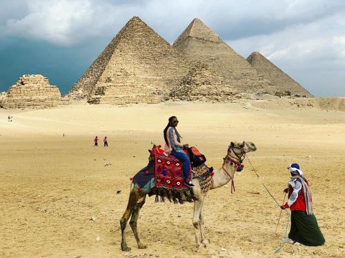 a man riding a camel in front of the pyramids at Draz pyramids view Bed & breakfast in Cairo