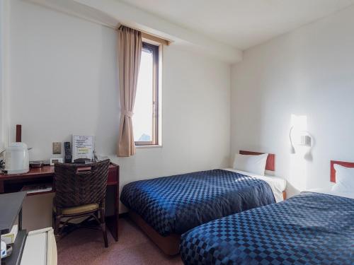 ein Hotelzimmer mit 2 Betten, einem Schreibtisch und einem Fenster in der Unterkunft Matsue Urban Hotel Lake Inn in Matsue