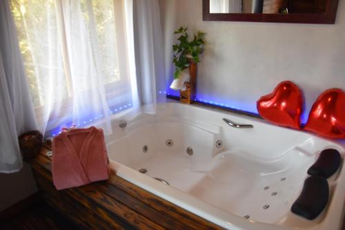 a bath tub with red hearts on top of it at Pousada Recanto Vale da Serra Chales in São Francisco de Paula