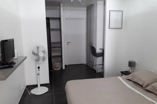 - une chambre avec un lit blanc et un ventilateur dans l'établissement Logement neuf de 40 m², équipé et confortable, à Croix-Chapeau