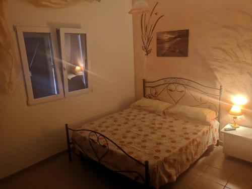 um pequeno quarto com uma cama e 2 janelas em B&B Angolo Magico em Baia Di Gallipoli