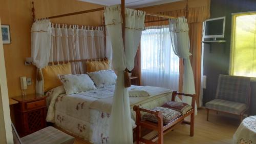 um quarto com uma cama de dossel e uma cadeira em Hotel y Cabañas La Rosa Nautica em Pichidangui