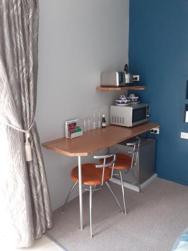 a desk in a room with two chairs and a microwave at J&D Cottage in Kerikeri