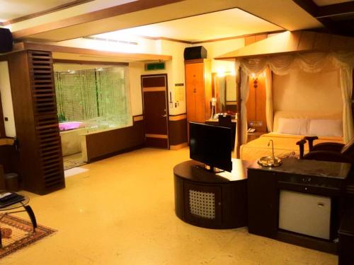 a room with a bedroom with a bed and a television at Swan Lake Motel in Guishan