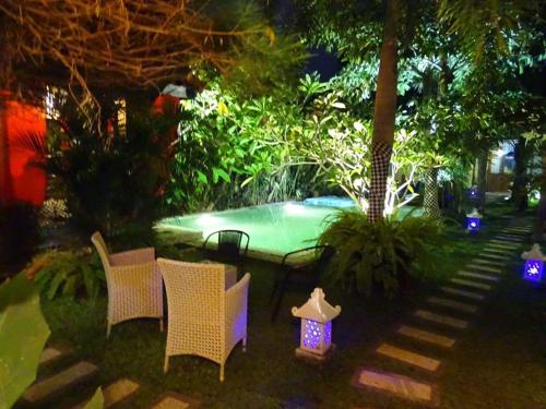 a backyard with a swimming pool with chairs and lights at Rosseno Villa in Yogyakarta