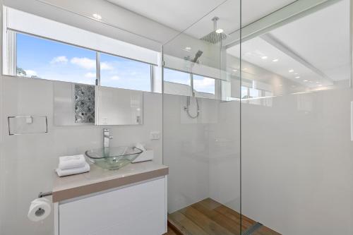 een badkamer met een wastafel en een glazen douche bij Wantima Hastings St 1 Bedroom Unit in Noosa Heads