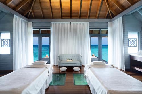 três camas num quarto com o oceano em Huvafen Fushi em Atol de Malé Norte